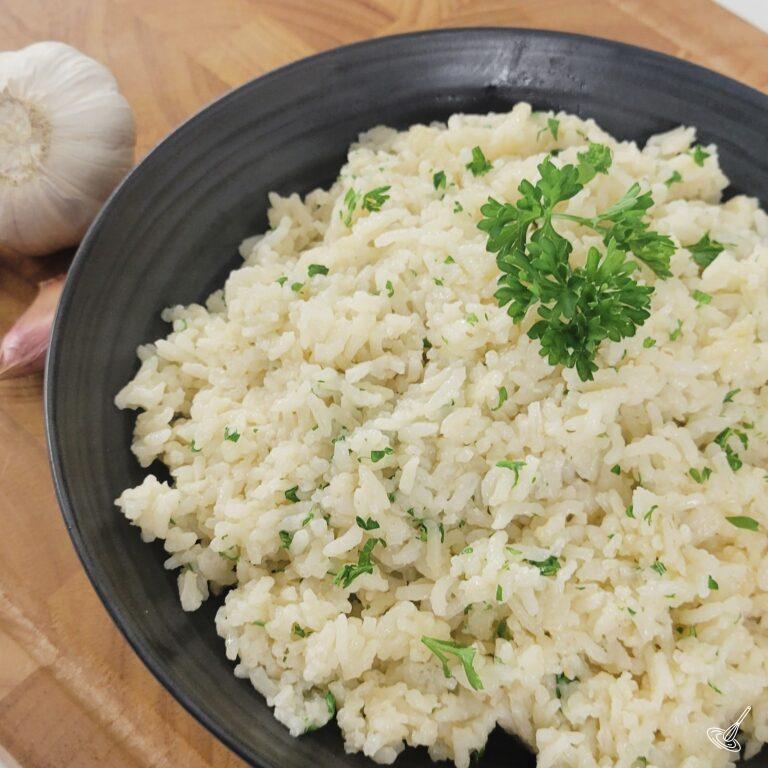 This is an image of cooked buttered garlic rice inside of a black bowl.