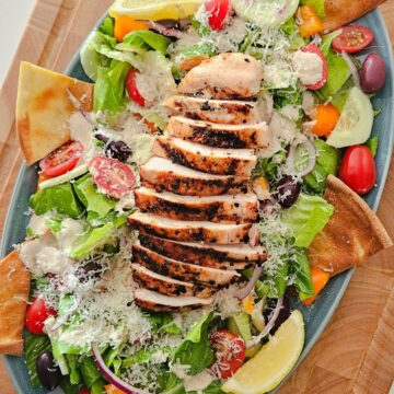 This is an image of a Greek Caesar Salad with a grilled chicken breast on top.
