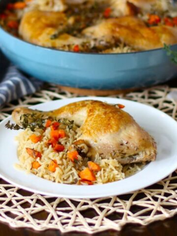 A cooked quarter chicken on a plate with rice.