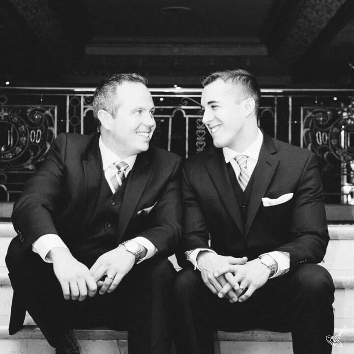 Black and White picture of 2 men wearing suits, sitting down.