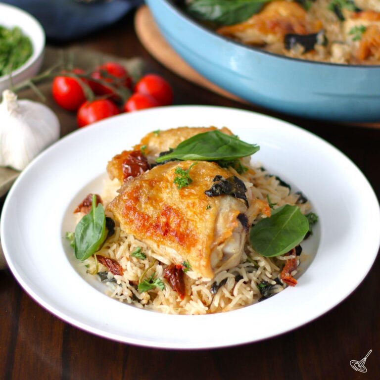 Baked chicken thigh on top of a bed of rice on a plate.