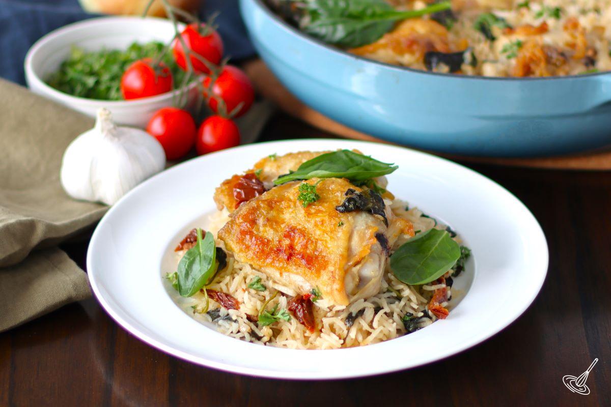 Tuscan Chicken Thighs with rice on a plate.