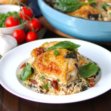 Tuscan Chicken Thighs with rice on a plate.