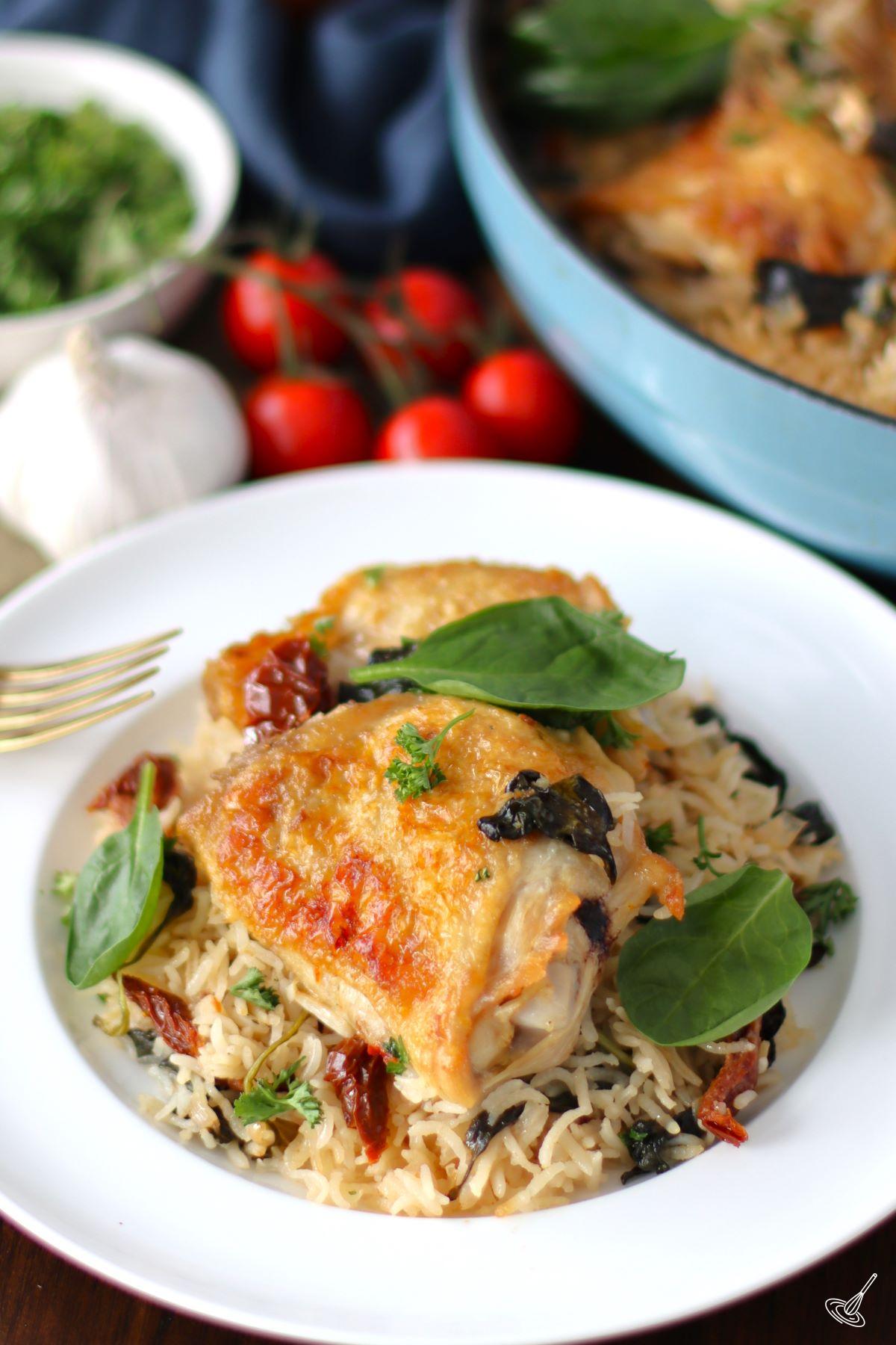 Tuscan Chicken Thighs with rice on a plate.