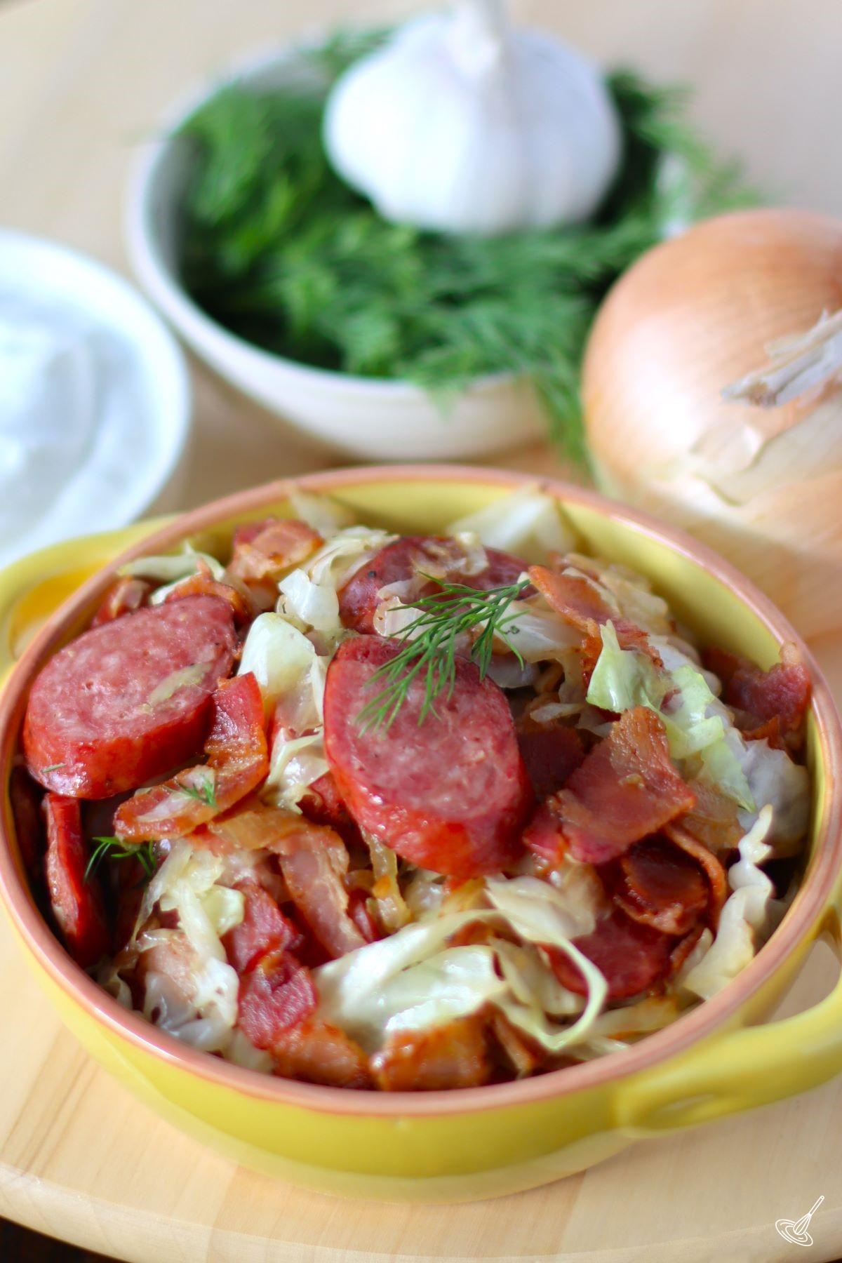 Fried Cabbage with bacon and sausage inside of a serving dish.