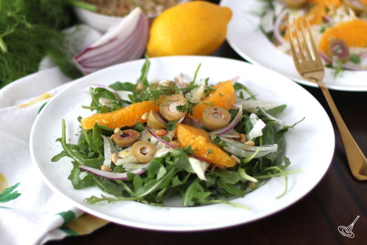 A Sicilian Salad on top of arugula on a white plate.