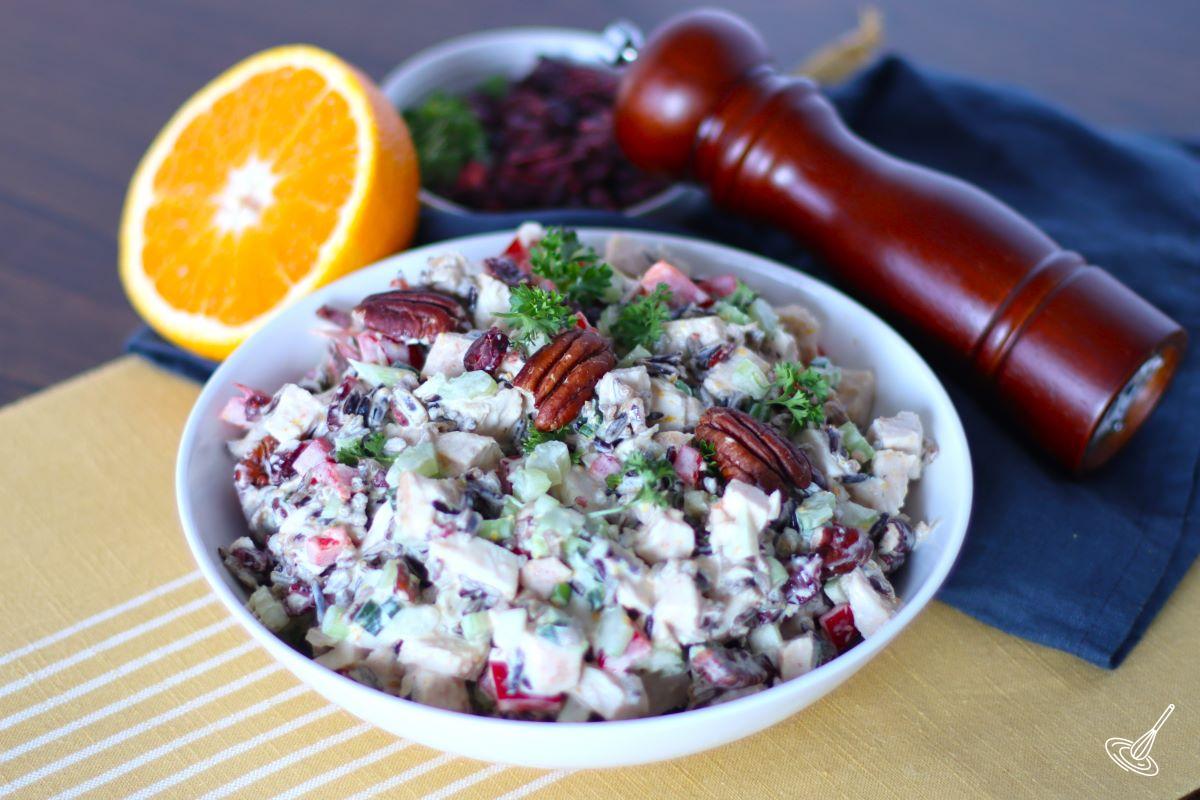 Chicken salad in a large bowl with toasted pecans on top. 