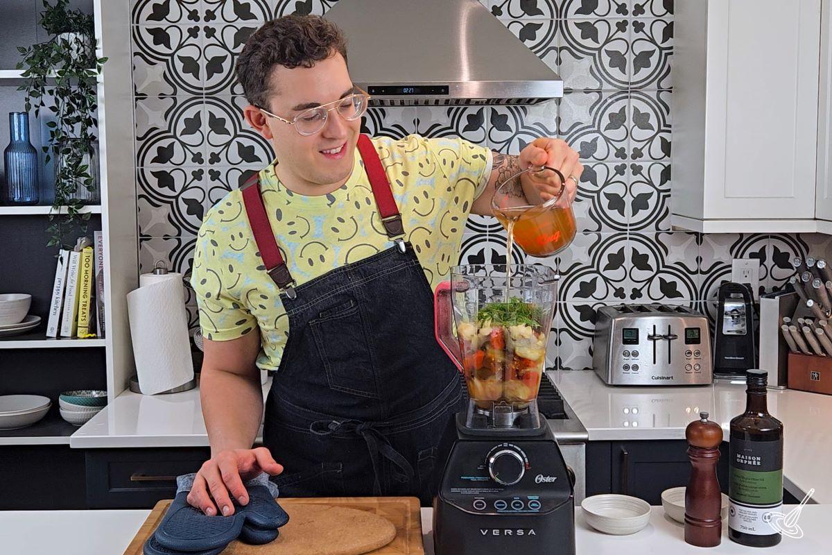 Someone pouring vegetable broth inside of a blender. 