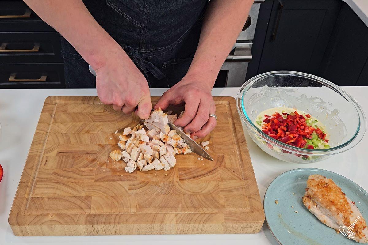 Someone chopping a chicken breast in small cubes.