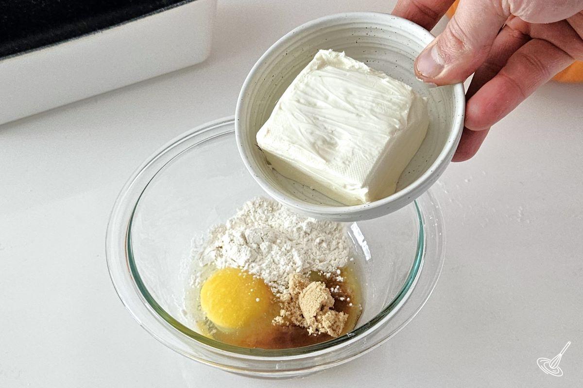 Someone combining cream cheese, egg, flour and sugar in a small bowl.