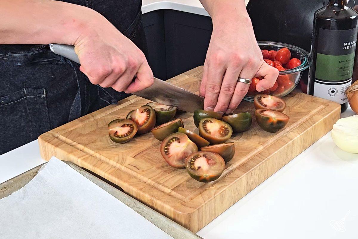 Someone cutting tomatoes in half.