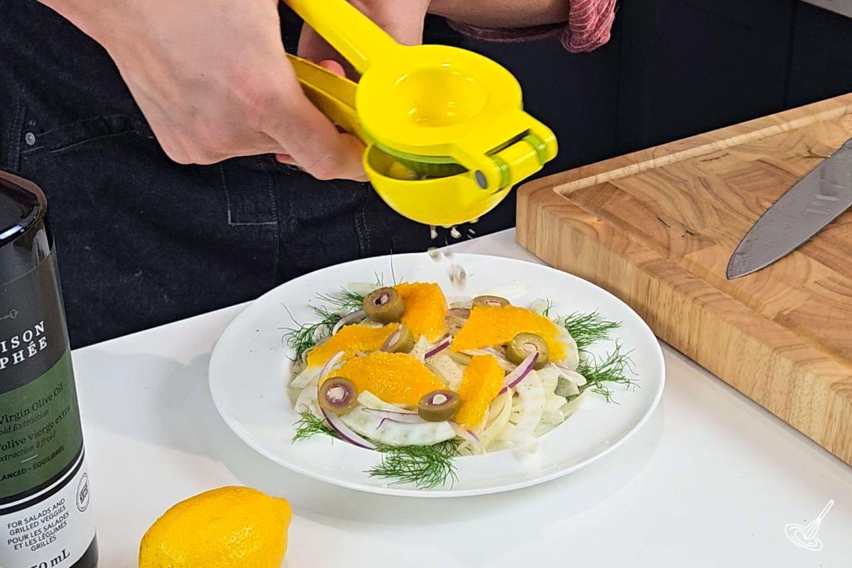 Someone squeezing fresh lemon juice on a salad.