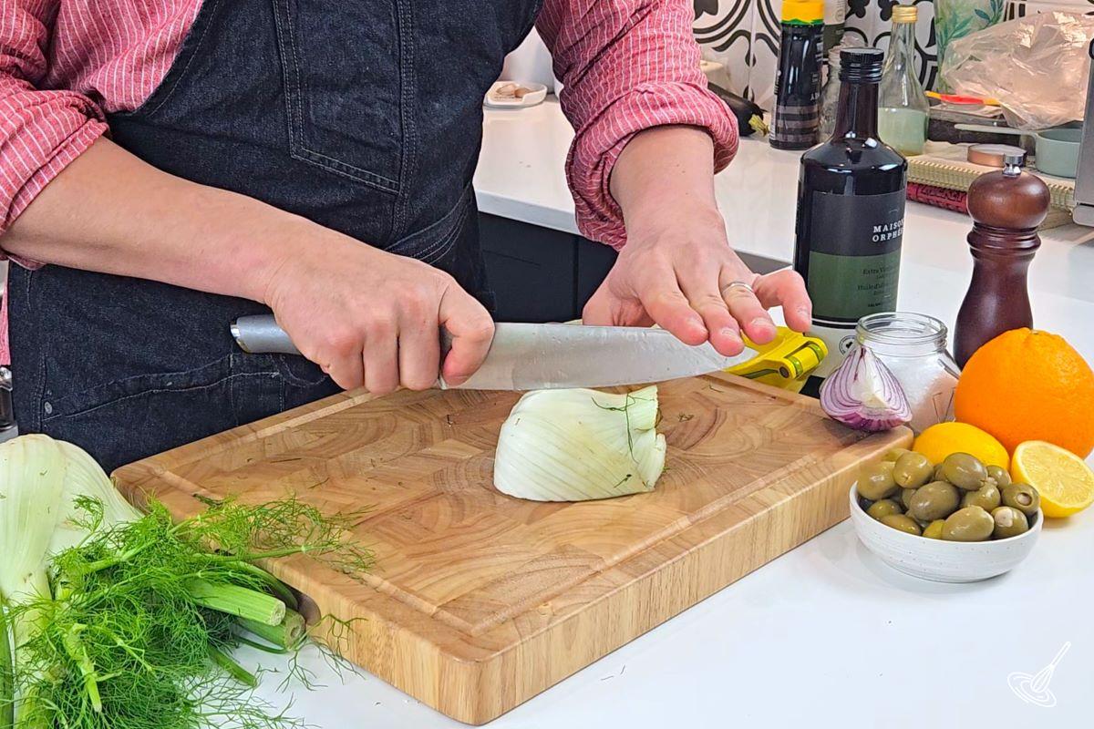 Someone cutting a fennel bulb in quarters. 