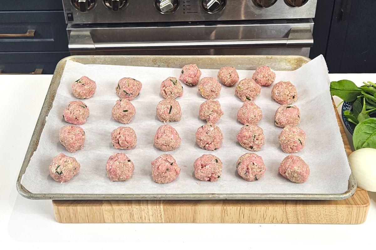 Turkey meatballs on a parchment paper lined baking tray. 