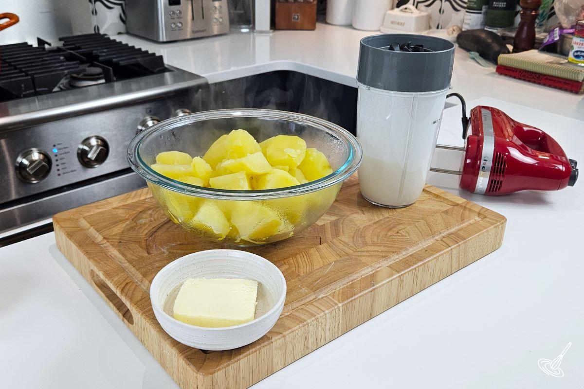 A large bowl of cooked potatoes ready to be mashed with butter and cottage cheese.