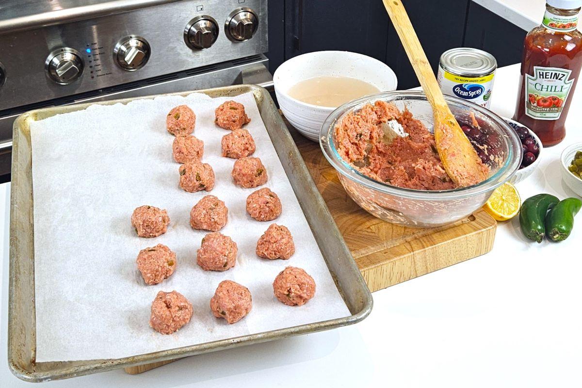 Meatballs being shaped and placed on a baking tray.