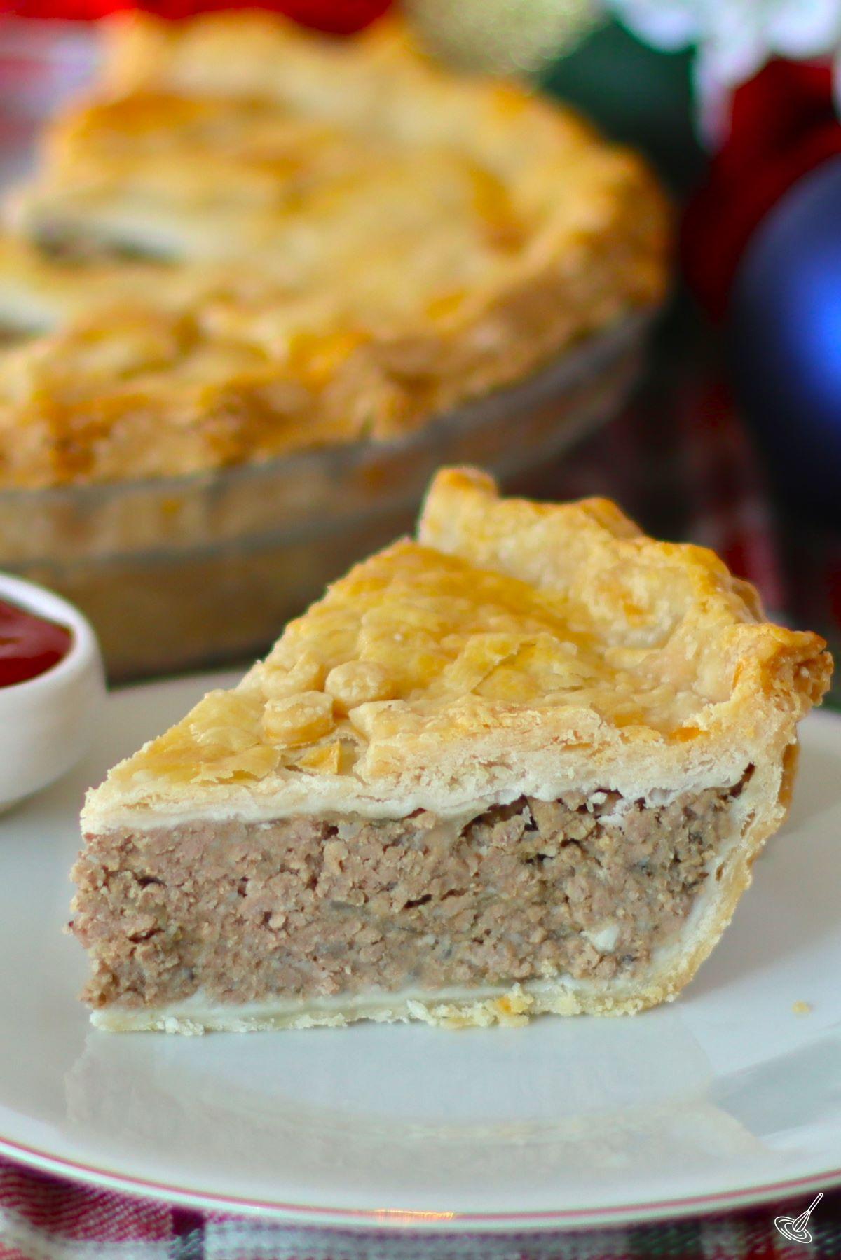 A slice of Traditional French Canadian Tourtière on a plate with a side of ketchup.