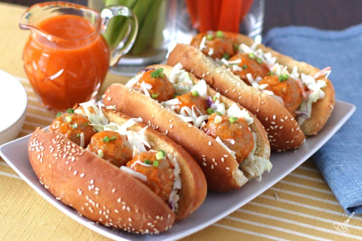 Buffalo Turkey Meatball Sub on a plate with a side of buffalo sauce. 