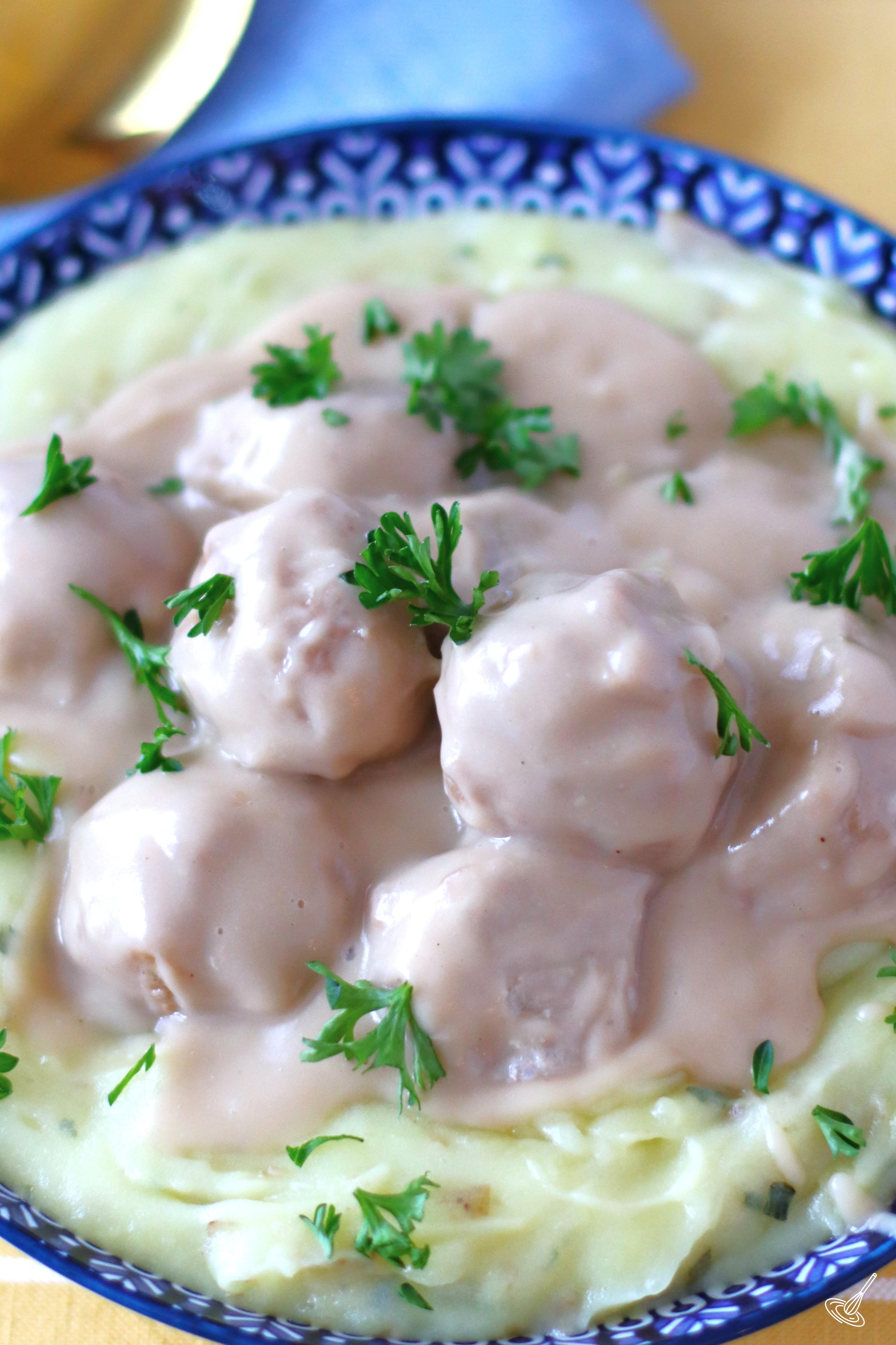 Turkey Swedish Meatballs on top of mashed potatoes in a serving dish.