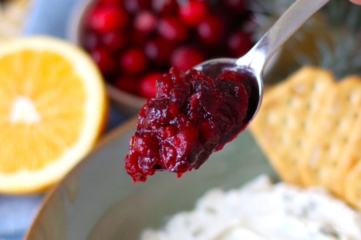 A spoonful of cranberry filling, being held over a bowl of jalapeno cream cheese filling.