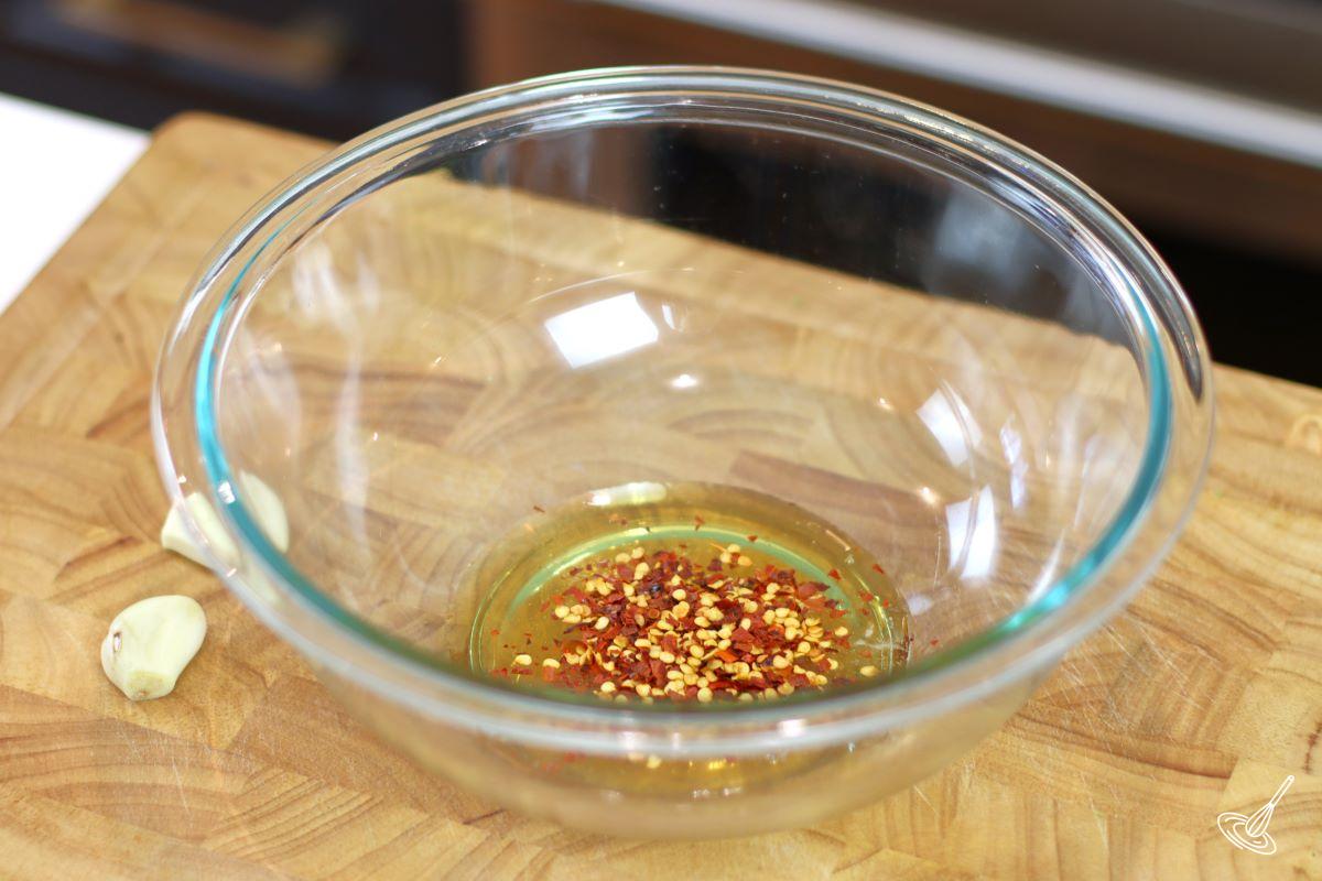 A large glass bowl containing liquid honey and hot chili flakes. 