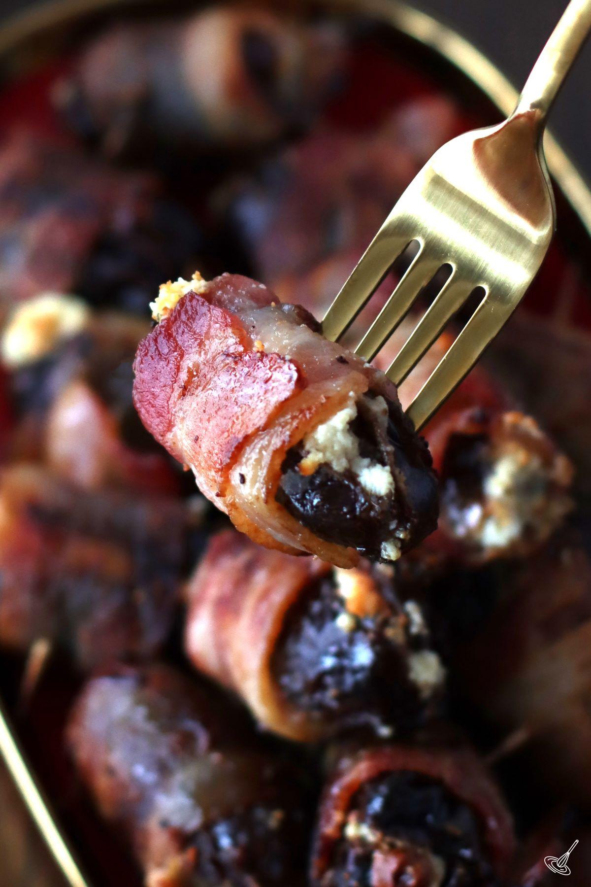 A Dates Stuffed with Goat Cheese being held by a fork.