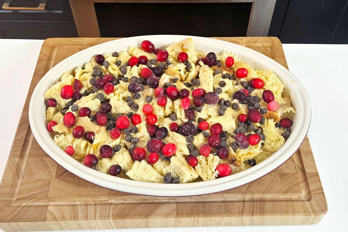 Cubed Panettone in a dish, covered in cranberries and chocolate chips. 