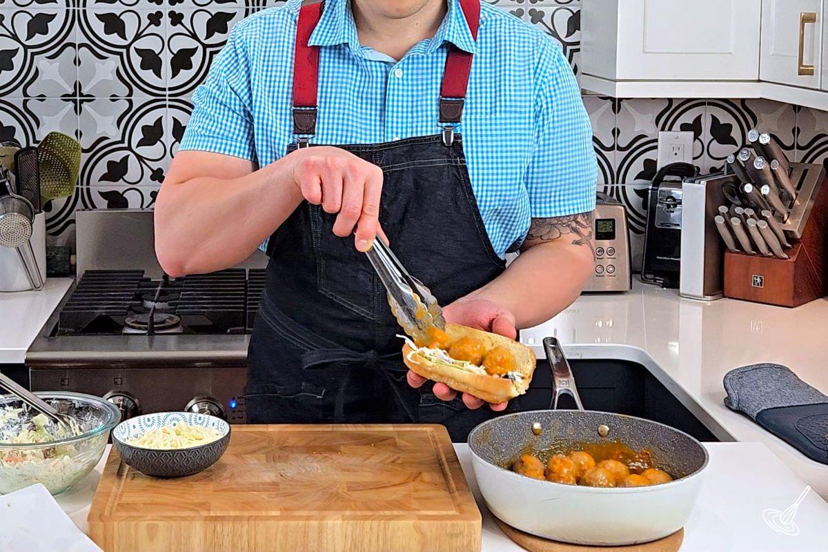 Someone assembling a Buffalo Turkey Meatball Sub.
