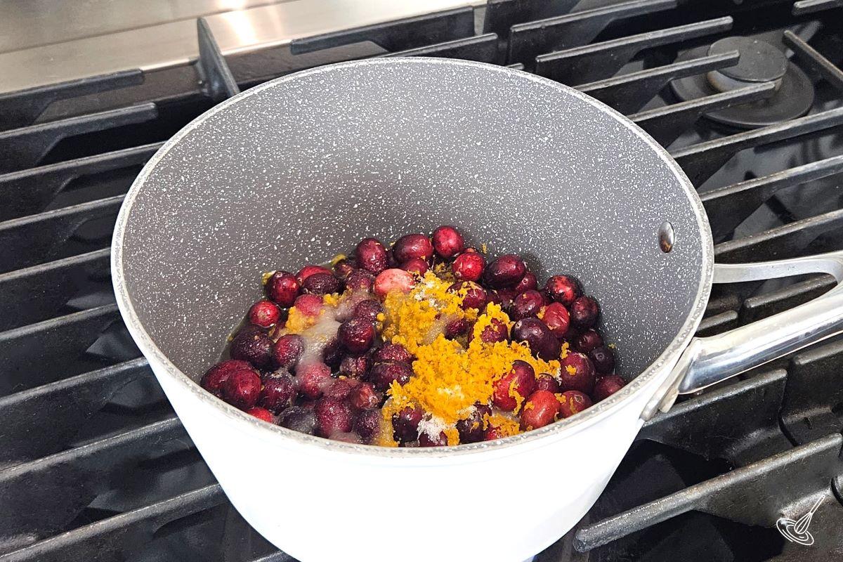 Fresh cranberries and orange zest in a sauce pan. 