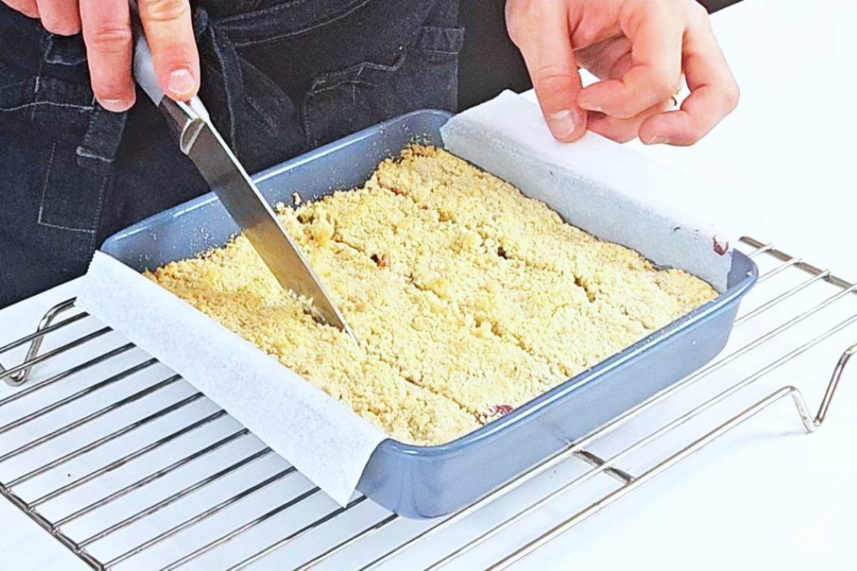 Someone cutting up Cranberry Shortbread Bars inside of the baking pan. 