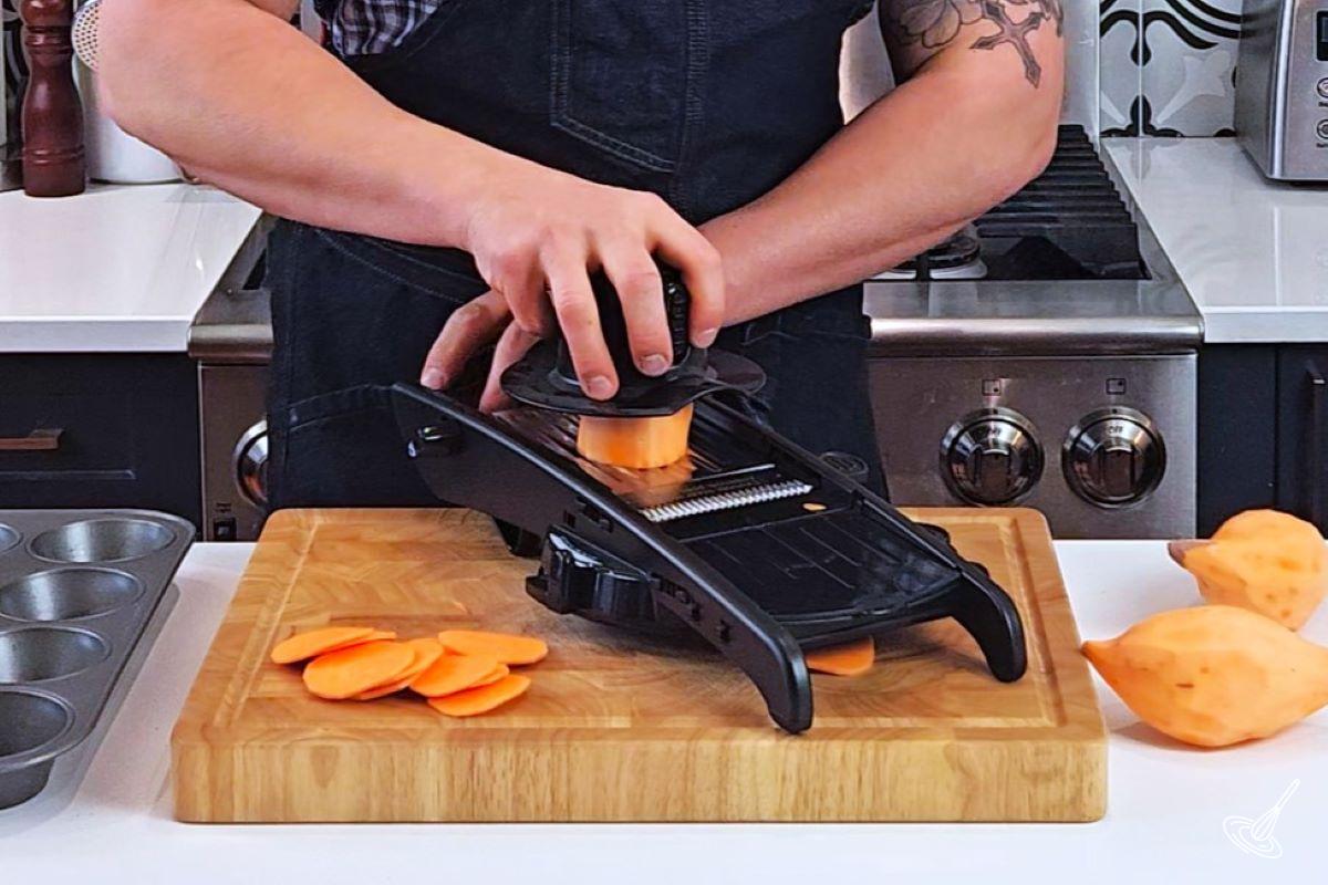 Someone slicing sweet potatoes with a mandolin.