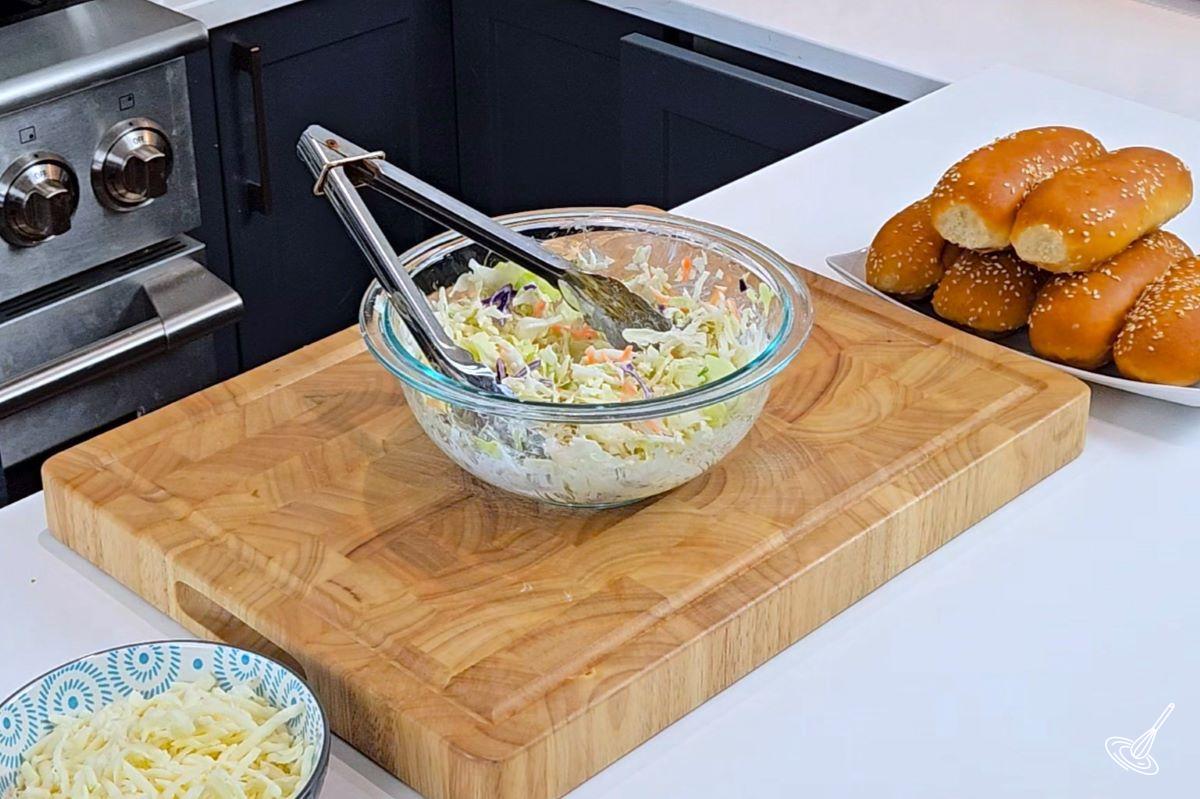 Someone mixing a bowl of coleslaw in a bowl.