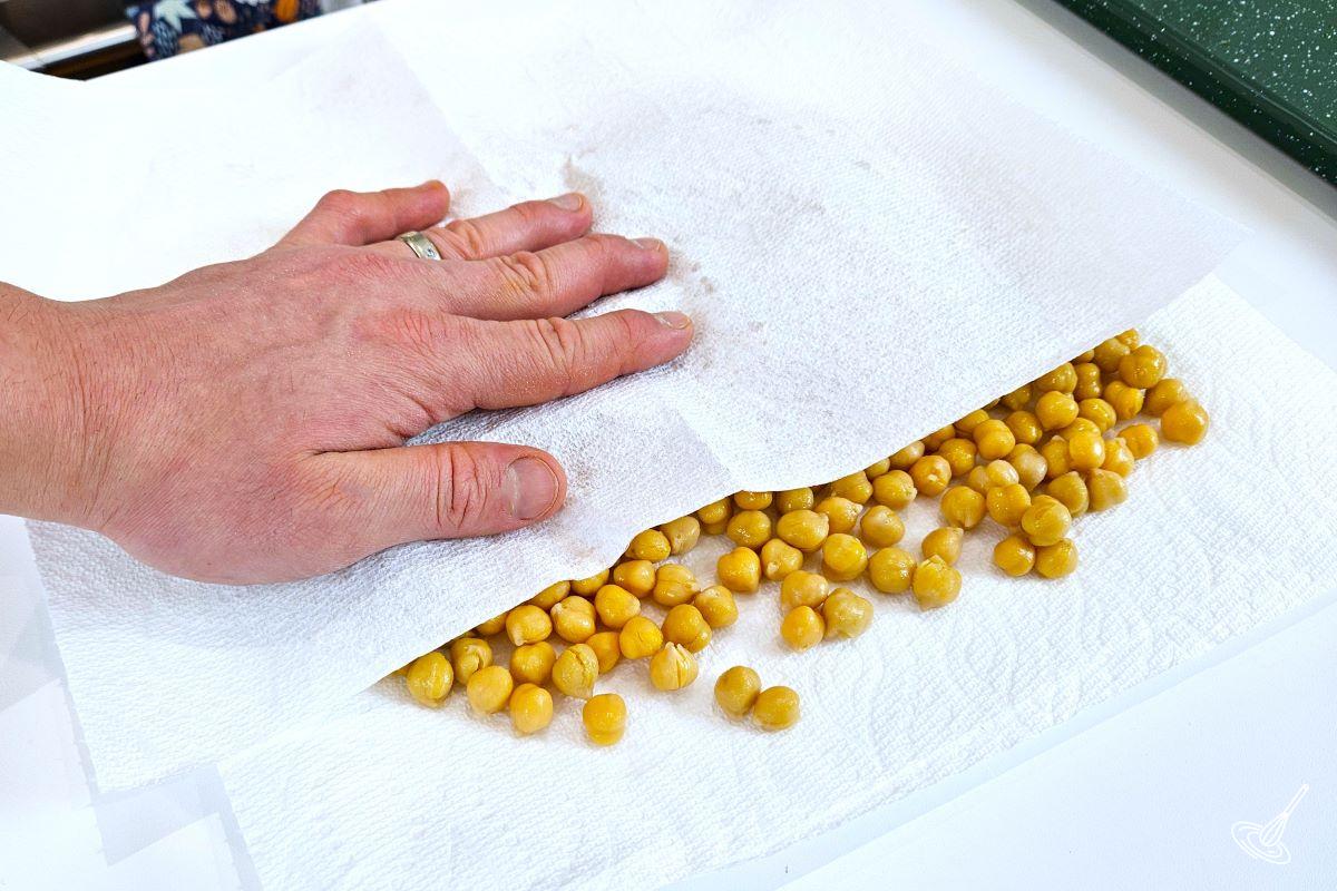 Someone rubbing chickpeas in between sheets of paper towel.