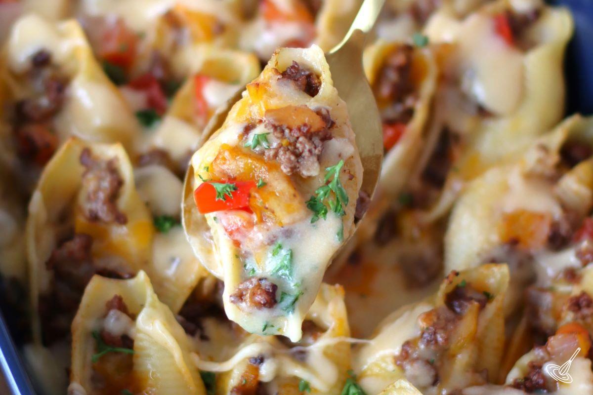 Someone scooping up a Philly Cheesesteak Stuffed Shell with a spoon.