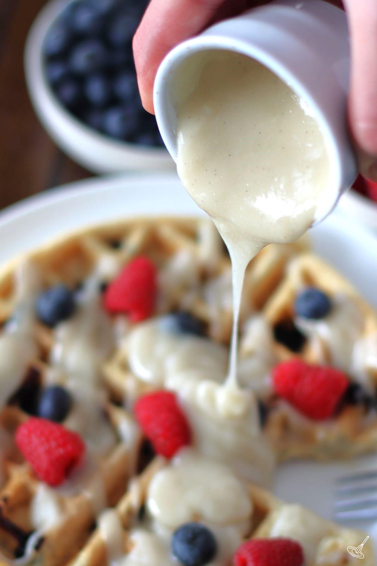 Waffle Sauce being poured over a waffle with berries. 