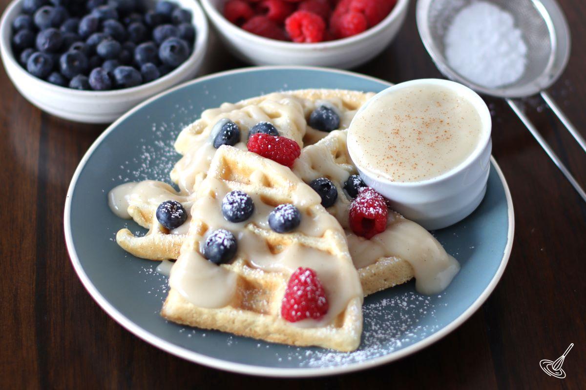 A place of waffles drizzled in waffle sauce with fresh berries.