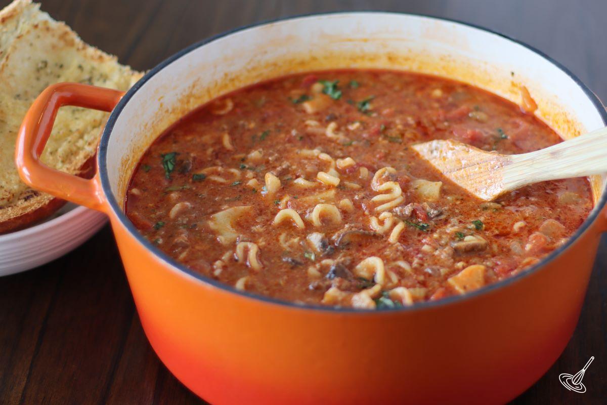 One Pot Lasagna Soup on a table with a large wooden spoon. 
