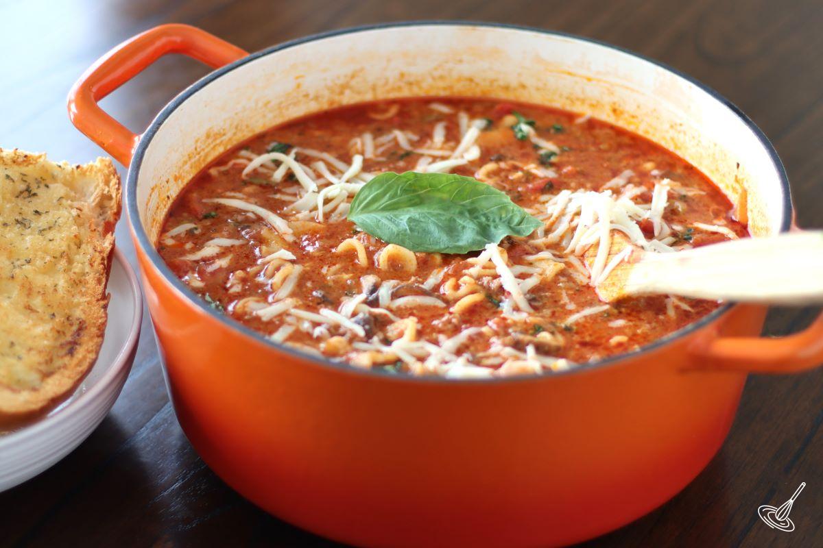 A large pot of lasagna soup garnished with grated mozzarella. 