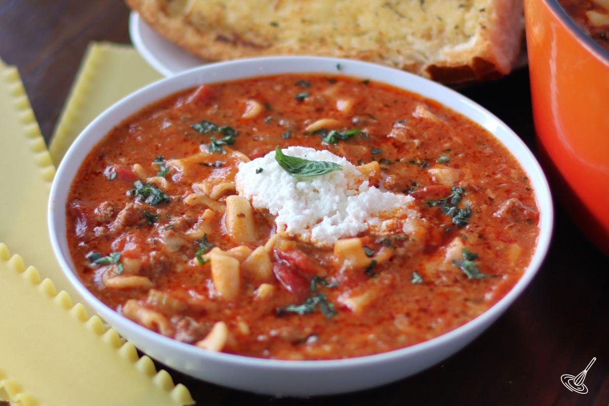 A bowl of One Pot Lasagna Soup, garnished with ricotta cheese and fresh basil.
