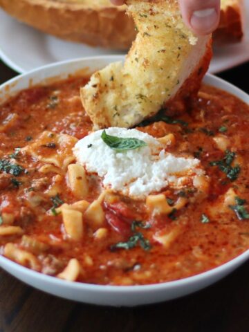 One Pot Lasagna Soup in a bowl with a piece of garlic bread.
