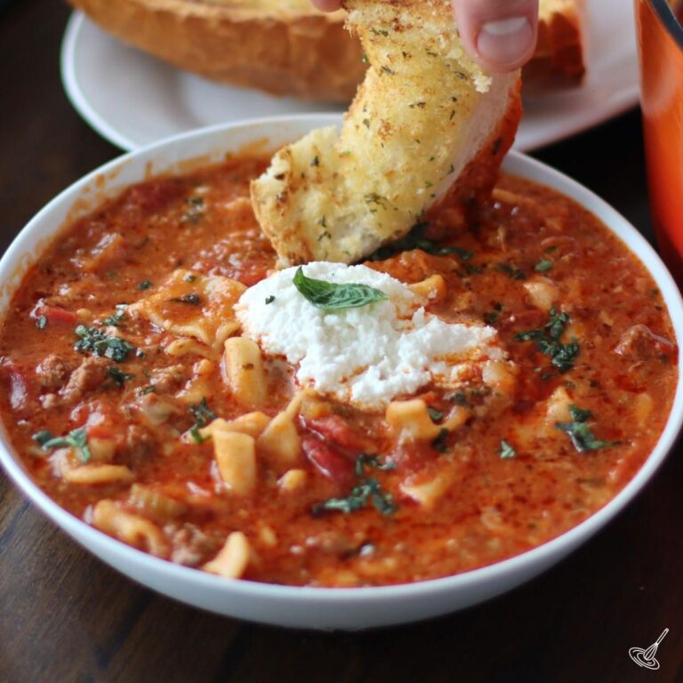 One Pot Lasagna Soup in a bowl with a piece of garlic bread.