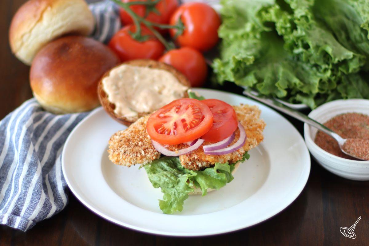 A Crispy Cajun Chicken Sandwich on a plate without the top part of the bun. 