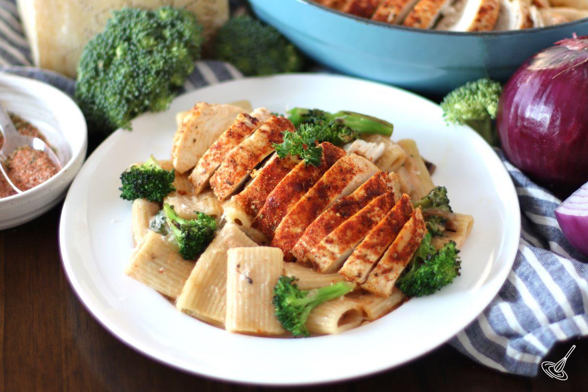 A portion of Cajun Chicken and Broccoli Alfredo on a white plate.