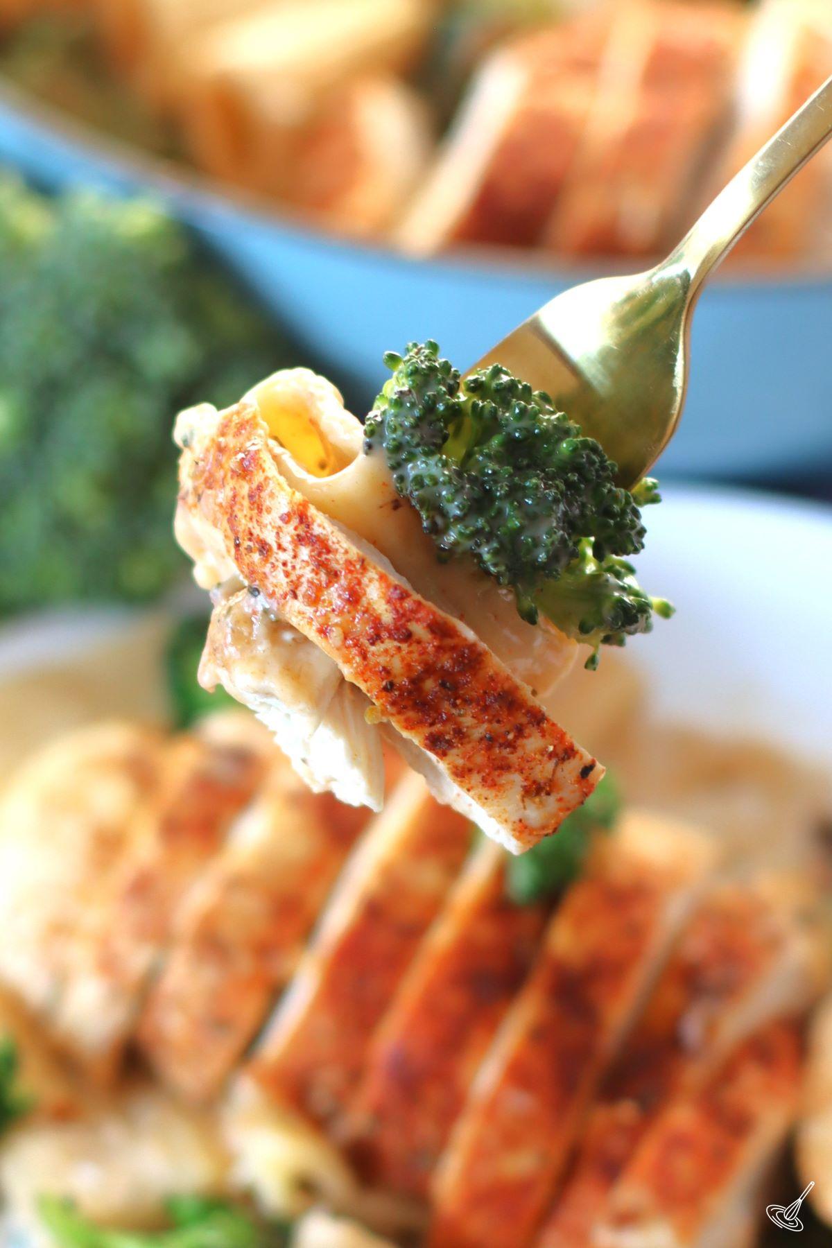 A fork holding Cajun Chicken and Broccoli Alfredo. 