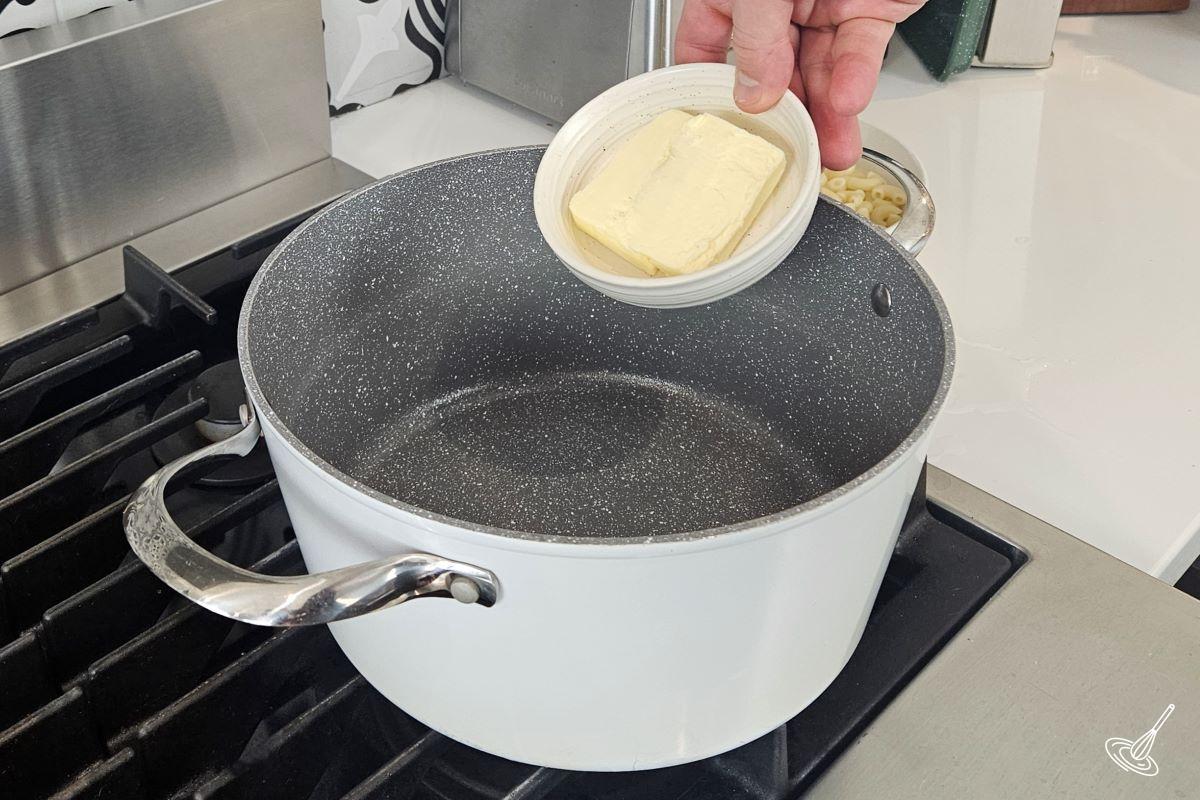 Someone adding butter to a large pot. 