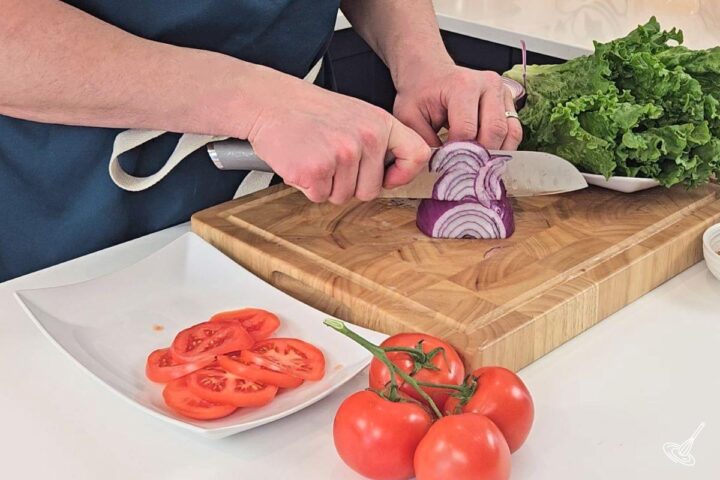 Someone cutting thin slices of red onion.
