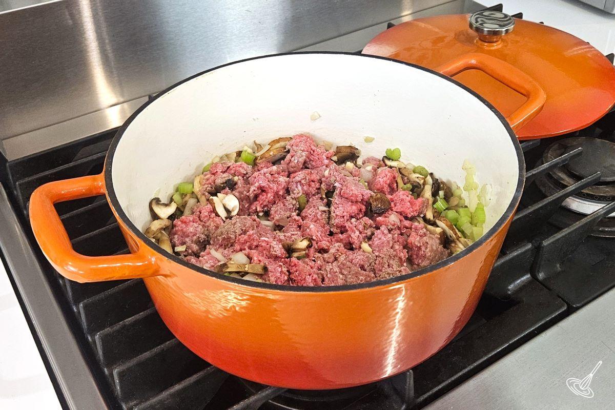 Broken down ground beef, cooking in a large pot. 