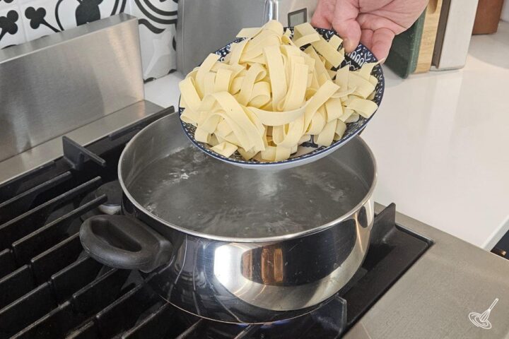 Someone placing pasta in a pot of boiling water. 