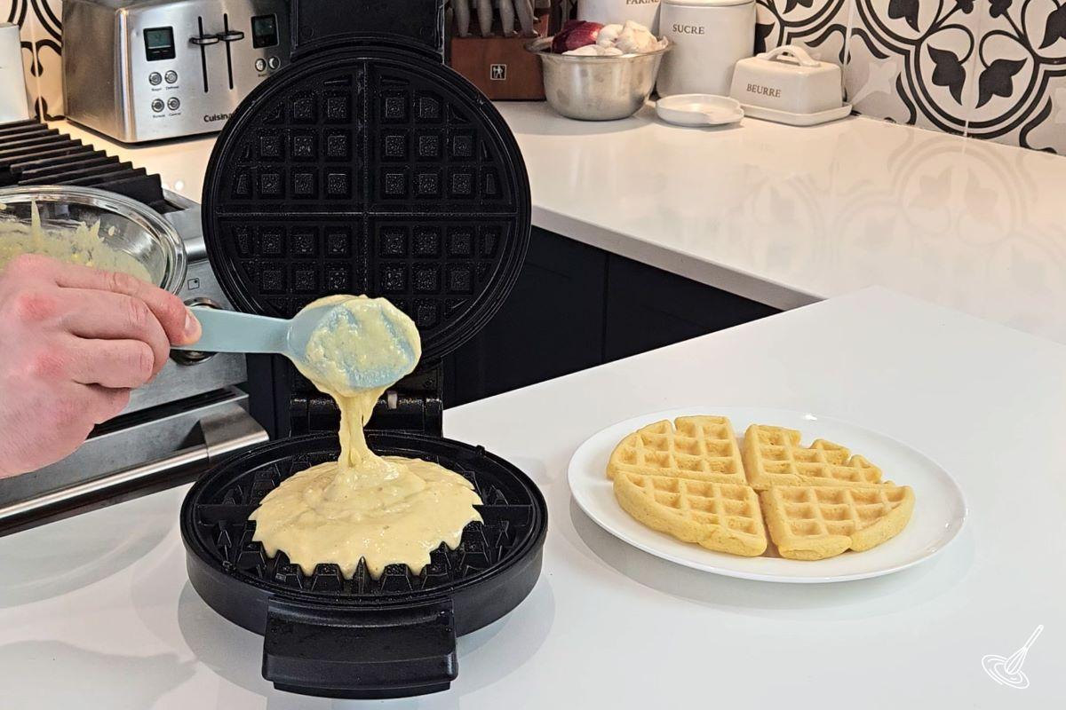 Someone pouring waffle batter in the waffle iron.