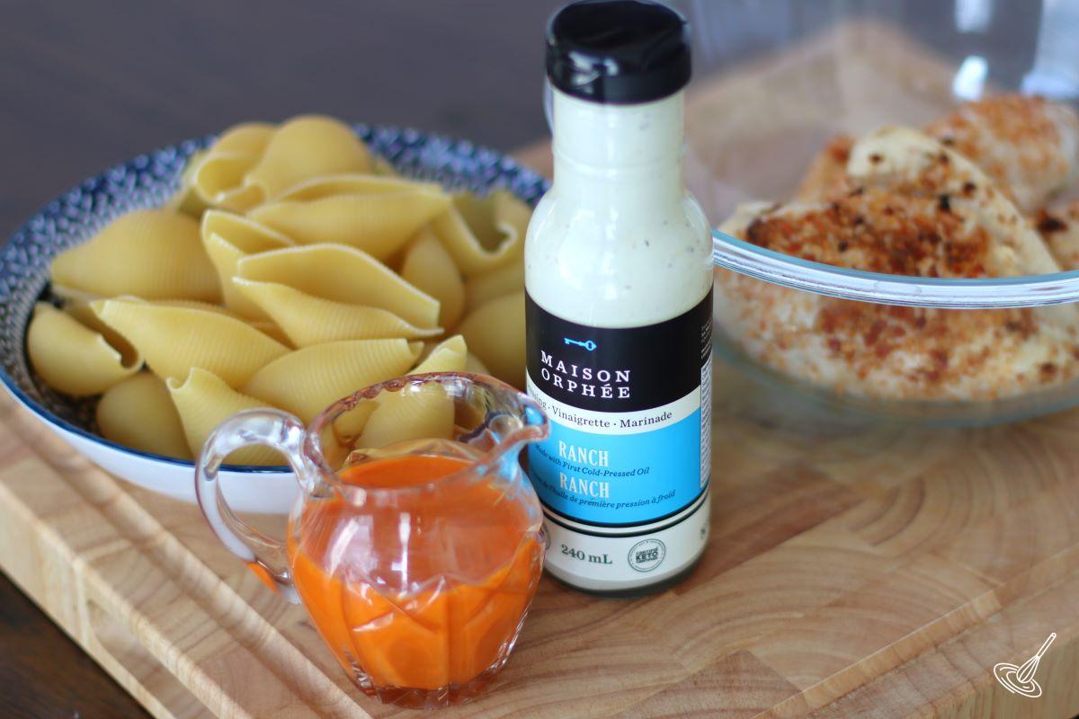 A bottle of ranch dressing and a container of buffalo sauce. 